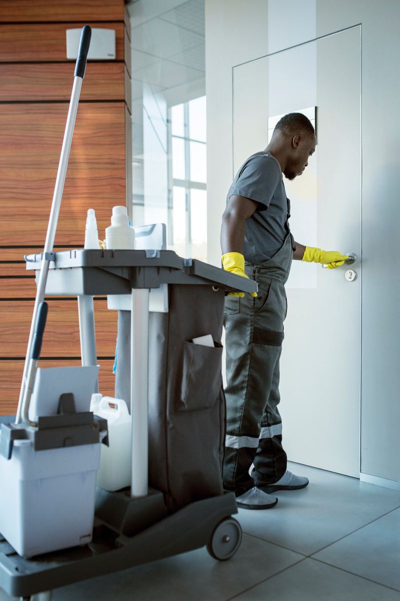 Cleaner with a cleaning trolley at a door