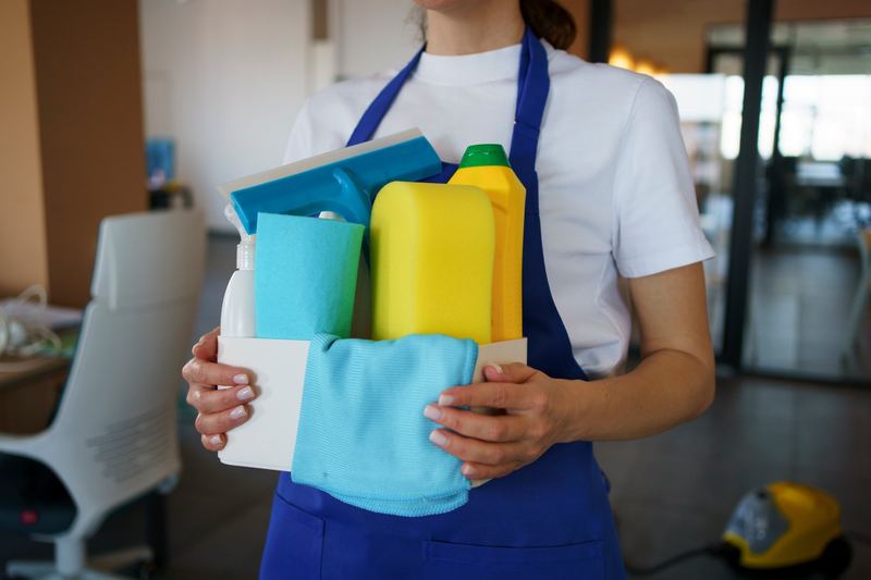 Cleaner carrying a caddy of cleaning supplies